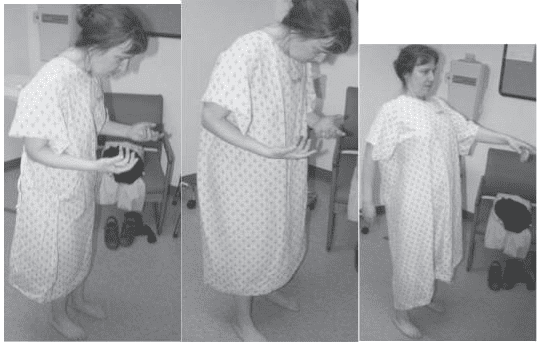 A woman in hospital gown holding something and standing.